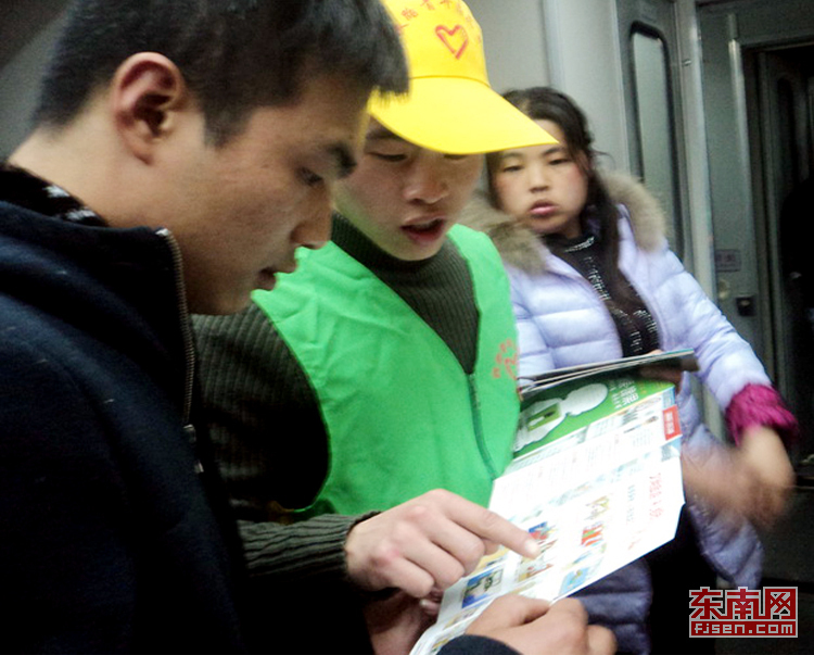志愿者在列車上發放宣傳手冊(通訊員丁輝攝)