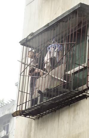 昨日，九龍坡馬王鄉，唐莉抱著2歲的兒子站在防盜窗上等待營救 